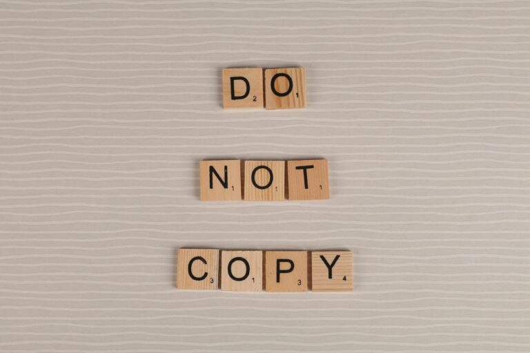 Close-up of wooden tiles spelling 'Do Not Copy' on a textured surface.