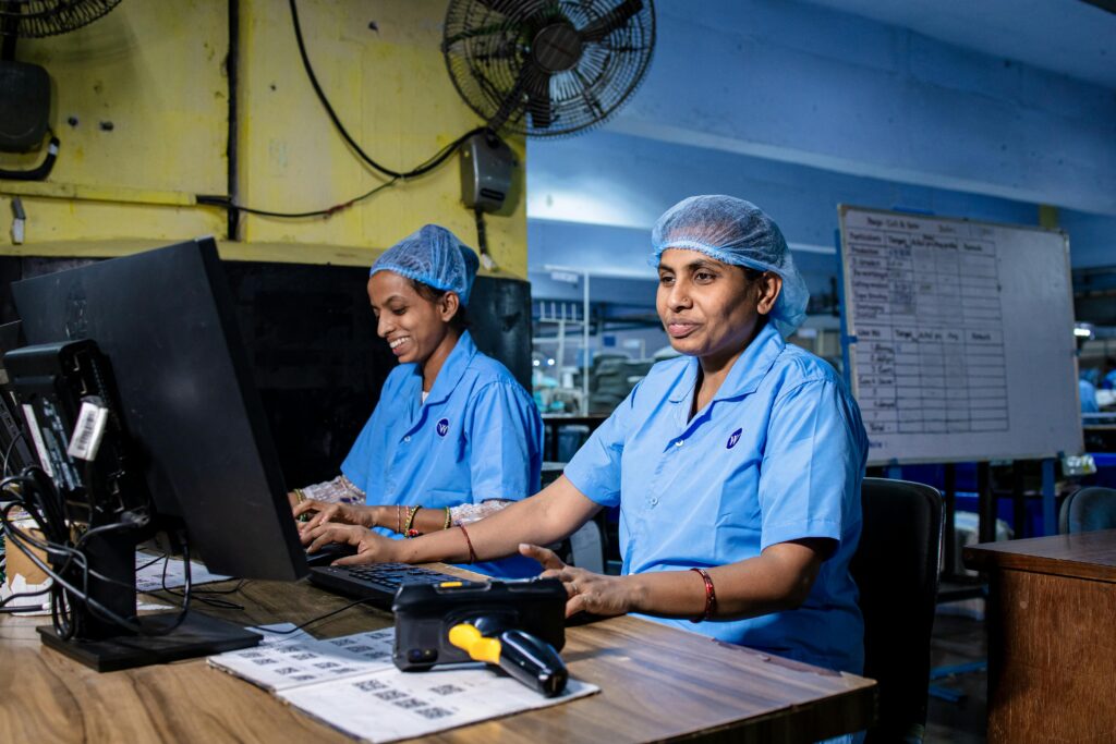 Two women working at computers in a textile factory, showcasing teamwork and industry precision.