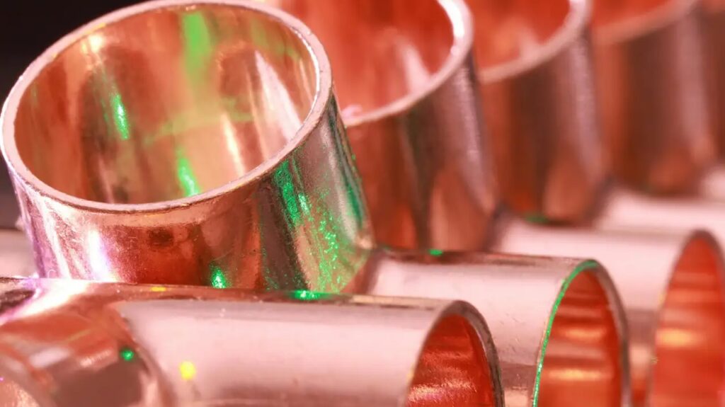 Copper plumbing fittings arranged in a row, showcasing metallic texture and industrial detail.