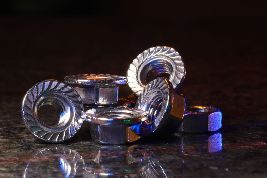 Artistic close-up of metal nuts on a reflective surface with colorful lighting and reflections.