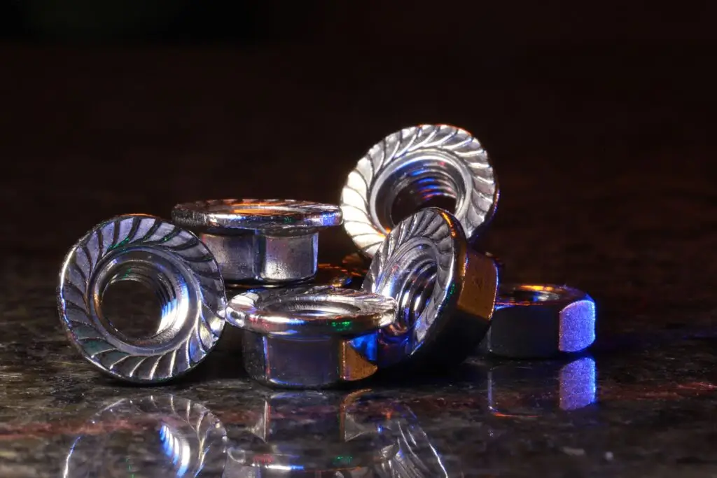 Artistic close-up of metal nuts on a reflective surface with colorful lighting and reflections.